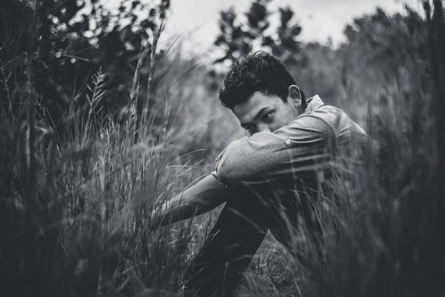 zwart wit foto van een man zittend in het gras