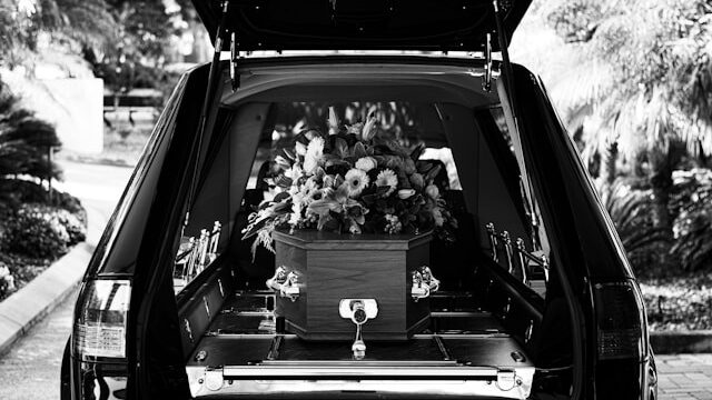 Een begrafenis auto waar een grafkist in ligt 
