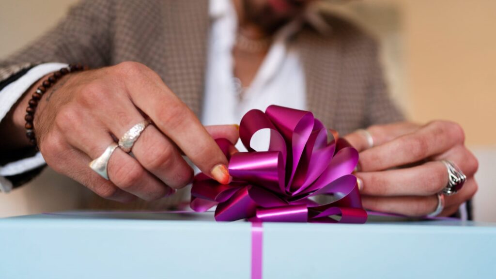 Hand die een paarse strik bevestigt op een cadeau als persoonlijk gebaar